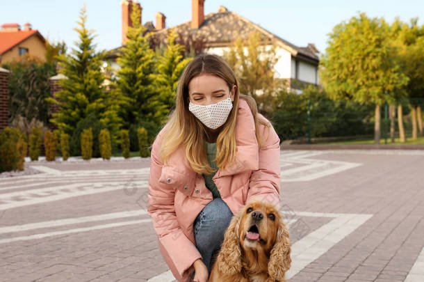 戴着防护面罩的女人在户外带着英国<strong>可卡</strong>犬。COVID-19大流行病期间的走狗