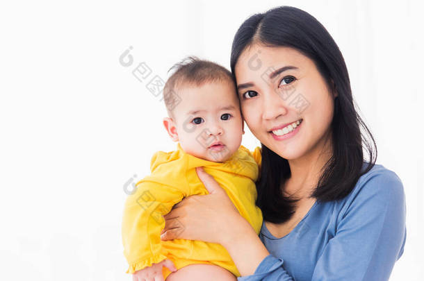 年轻美丽的亚洲母亲<strong>在家</strong>中抱着自己刚出生的孩子的画像，母亲抱着自己刚出生的孩子，幸福的家庭