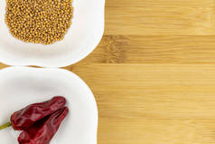 辣椒和芥末种子在白碗上的切菜板上