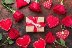 红玫瑰、礼品盒和木制背景的装饰纺织品心。情人节贺卡-图片