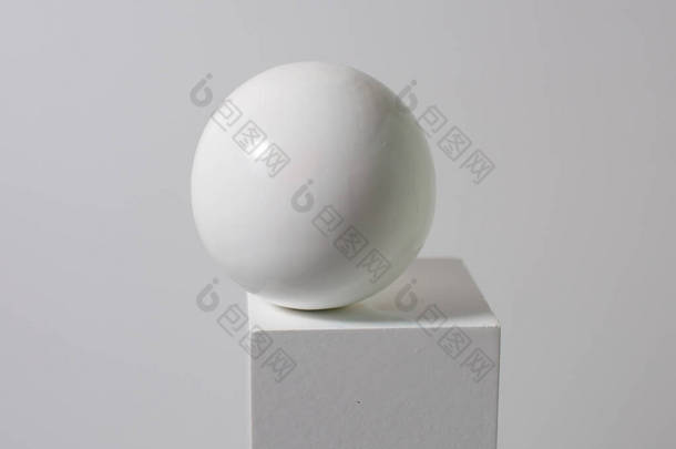 白色立方体上的白色球，白色背景上的白色球。美感简约的概念，汲取教训。复制空间.