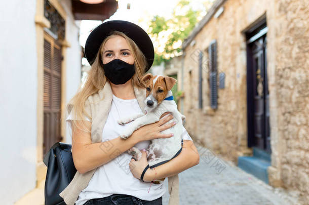 穿着防护面罩的游客手牵着狗，<strong>走</strong>在古城的科罗纳维鲁病新的旅游现实中。戴着口罩<strong>走</strong>路的女孩。与宠物<strong>一起</strong>旅行：与宠物<strong>一起</strong>旅行.