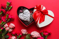 情人节漂亮的贺卡。心形礼品盒,心形装饰,红色背景花朵.俯瞰，平铺.