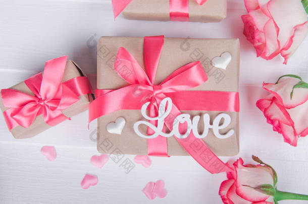 The word <strong>love</strong> in white letters on gift boxes with pink ribbons. Love concept, Valentine's day.