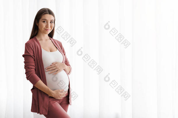 美丽的<strong>怀孕</strong>妇女站在家门口拥抱美女的画像