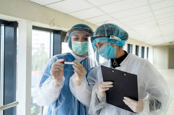 戴防护面具、戴护目镜和戴手套的医护人员在验尸官身上给病人写报告