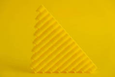 黄色的塑料建筑在黄色的背景上呈金字塔状。塑料细节的背景积木.玩具用明亮的小零件的零件.复制，空的文字空间.