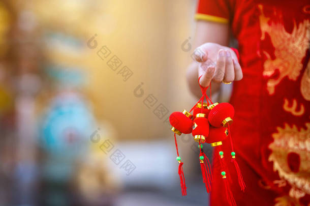 身穿红色中国传统旗袍装饰的亚洲小妇人特写，手持小灯笼装饰过年