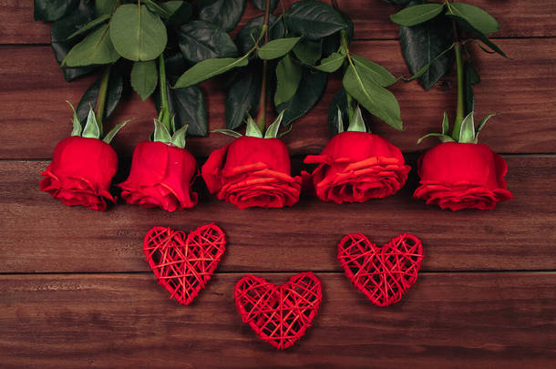 红玫瑰，红心，深色木制背景。情人节明信片的概念.