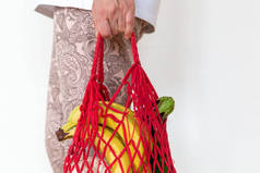 女人拿着装有杂货的袋子.红绳袋中的蔬菜和水果
