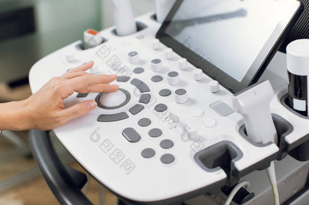 <strong>近</strong>距离拍摄现代医疗设备,超声波扫描仪在工作.专业女医生的手按超声波控制面板上的按钮
