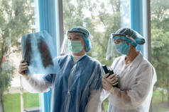 两名年轻的医生正在医院工作，他们正在检查他们的肺部X光图像。怀疑感染肺炎