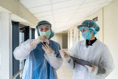 现代门诊部穿着医用防护服的夫妇护士在试管中保存血液样本