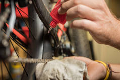 在自行车链条上涂上一层特殊的油，用于自行车链条。一个人的手在拖着一个毫巴链子，一滴油在油罐的喷嘴前被看见.