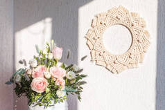 白色的墙上挂满了粉红色的玫瑰花，上面挂着棉兰花壁饰。手工做的石榴花环。天然棉线生态家居装饰。复制空间