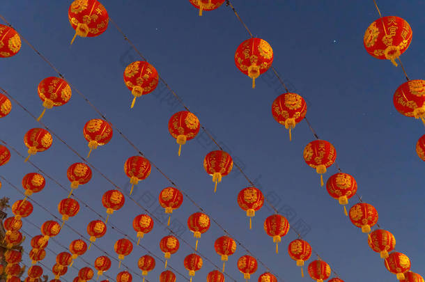 在亚洲农历新年文化中，中国红灯笼挂在中国庙宇户外彩灯上，背景为蓝天.