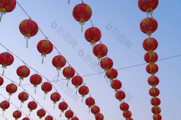 在亚洲农历新年文化中，中国红灯笼挂在中国庙宇户外彩灯上，背景为蓝天.