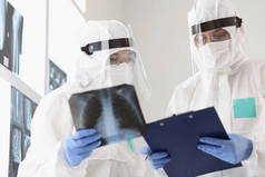 两名穿着防护服戴口罩的医生检查X光