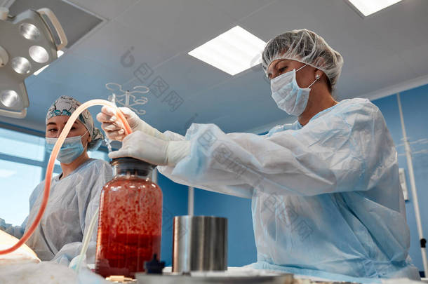 手术室实际环境下整形手术中的抽脂手术，显示手术中的外科医生组
