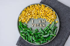 我是盘中的维根文字。素食、素食、健康生活方式、绿豆、黄玉米.健康的素食主义者。木制信件