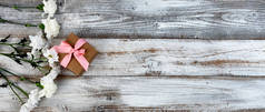 母亲节或情人节时，在乡村木板左边的真正的白花和礼品盒 