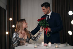 在浪漫的晚餐上，男人在餐馆里向心爱的女人献上玫瑰