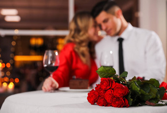 可爱的情侣们在餐厅庆祝情人节，聚精会神地围坐在红玫瑰桌旁图片
