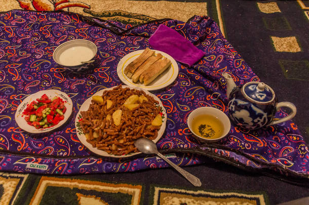 塔吉克斯坦的饭菜- -意大利面、面包、沙拉、酸奶和茶