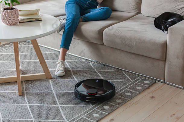 机器人吸尘器清洗地毯，女人的<strong>腿</strong>在沙发上休息在家