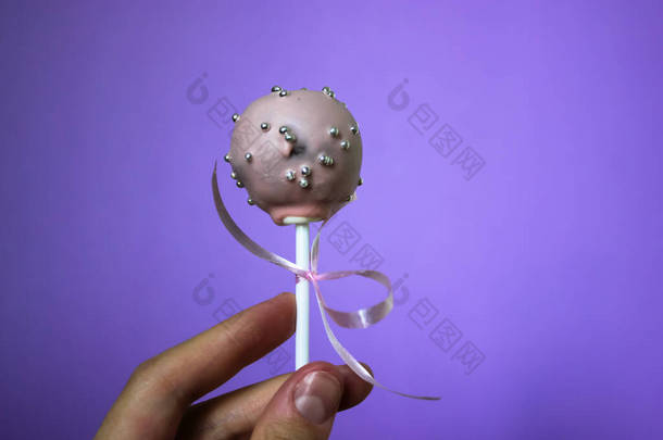 <strong>粉色</strong>巧克力蛋糕,带有草莓味,背景是<strong>紫</strong>色的.用彩带装饰的棒上的圆圆的蛋糕和点缀着银珠的糖果。一个甜蜜的款待。世界巧克力日.