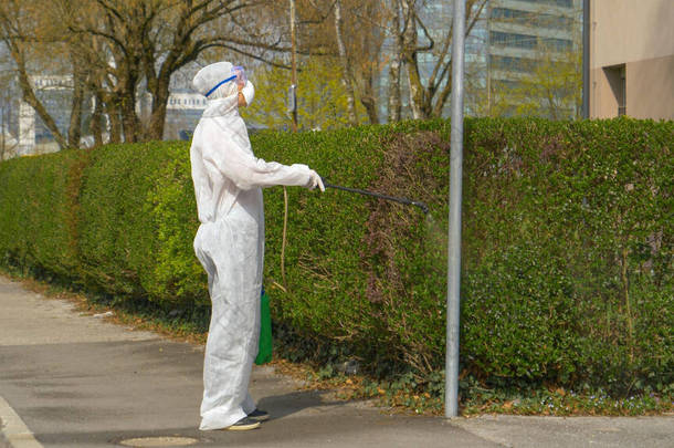 Virologist disinfects a street lamp and sidewalk during covid-19 outbreak.