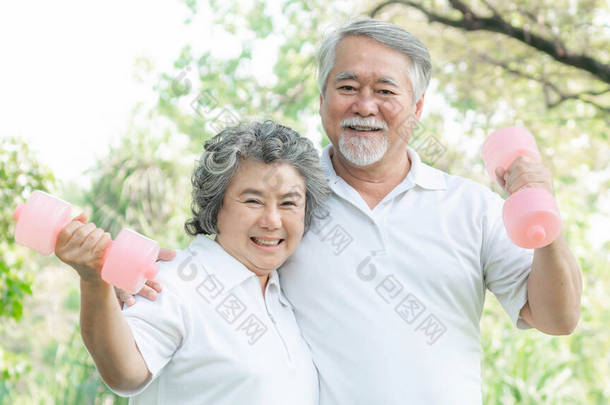 快乐的爱着亚洲的老年男子和亚洲的老年女子，带着哑铃在公园里锻炼，他们带着健康的<strong>笑容</strong>- -老年夫妇的概念