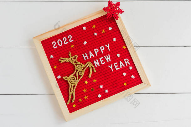 新的一年2022 。白色背景上有金鹿和红色片断的字母板。平躺在床上