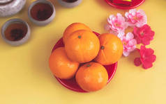 橙色的盘子放在模糊的粉红花朵旁边，背景上，是中国的吉祥水果，四周是模糊的花束