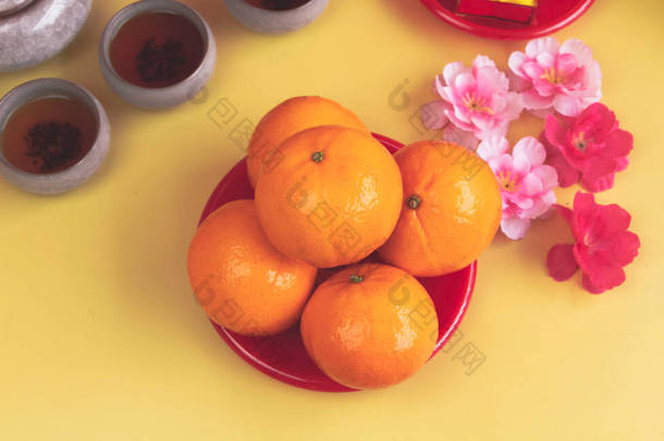 橙色的盘子放在模糊的粉红花朵旁边，背景上，是中国的吉祥水果，四周是模糊的花束