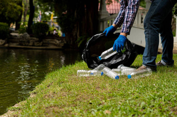 一个年轻人在公园拿起瓶子，那是塑料造成的环境污染.
