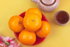 橙子放在红盘上，除了模糊的中国茶杯外，四周的灯光模糊了