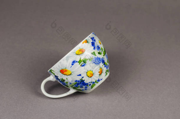 带有灰色背景的陶瓷茶杯的<strong>简约</strong>构图。漂亮的杯子装饰着白色和<strong>黄</strong>色的雏菊.