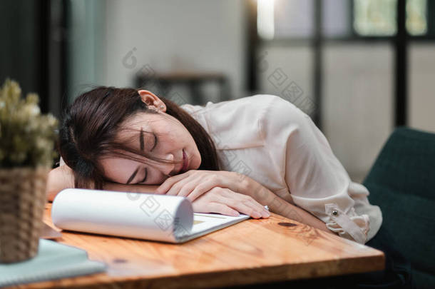 疲惫不堪，工作过度的女商人。工作时躺在桌子上的疲惫不堪的年轻女孩- -企业家、自由职业工人或有压力的学生