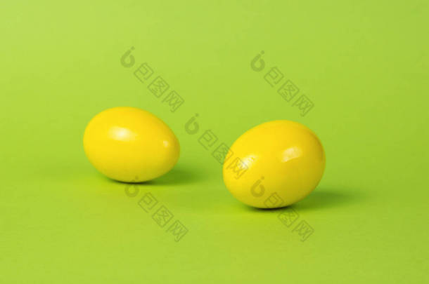绿色背景上的两个明亮的黄色蛋。鸡蛋的创意照片.