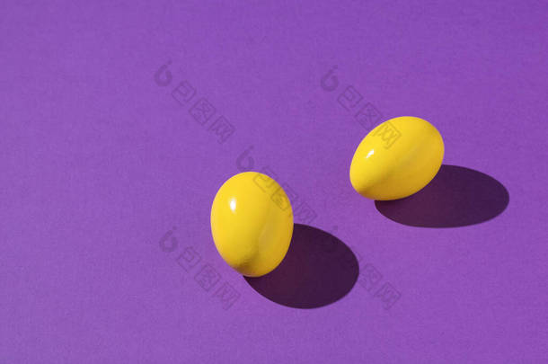 紫色背景上的两个明亮的黄色蛋。鸡蛋的<strong>创意照片</strong>.