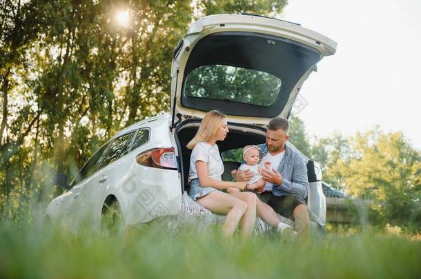 有三个身穿白衣的年轻人在野餐.美丽的父母和女儿在<strong>暑假</strong>期间开车旅行.