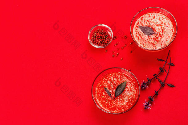 自制番茄汤。健康的素食，简约的概念。粉红色的胡椒玉米紫色的罗勒花明亮的红色衬垫背景，顶部视图