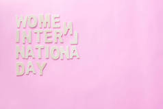 粉红背景下印有国际妇女节日期的木制字母设计.