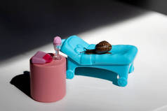 一条蜗牛在阳光下爬上一条长链。一条蓝色的长链和一条粉色的鸡尾酒桌。夏天在海滩度假