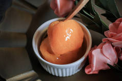 自制的橙色冰淇淋，粉红色的花，背景是古色古香的。冷夏季甜点.