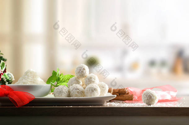 厨房餐桌，用椰子和白色厨房背景的碗为活动准备椰子球。1.横向构成.