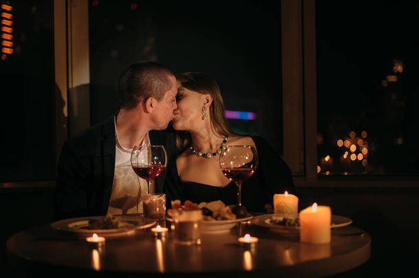 情人节两人共进晚餐，在餐桌上亲吻情侣，烛光下浪漫的约会，为家人、男人和女人庆祝情人节的红葡萄酒，以及情人节的庆祝<strong>理念</strong>