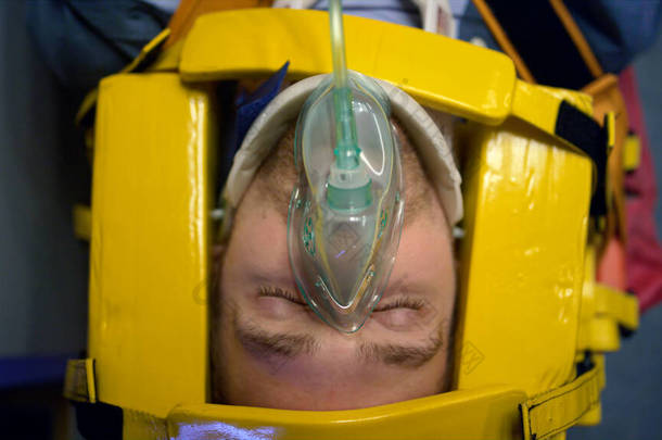 戴氧气面罩的男人躺在担架上.为人类提供急救的医护人员