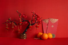 中国新年装饰品。橙子，叶子，红包，梅花红色背景.